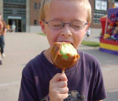 boy eating caramel apple on a stick