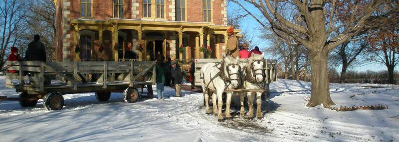 horse and wagon in snow in fron of Flynn Mansion with Christmas wreaths