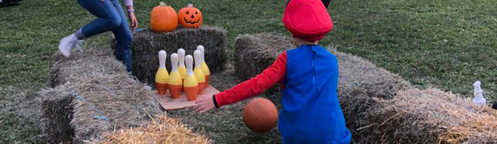 child in costume bowling with a pumpkin