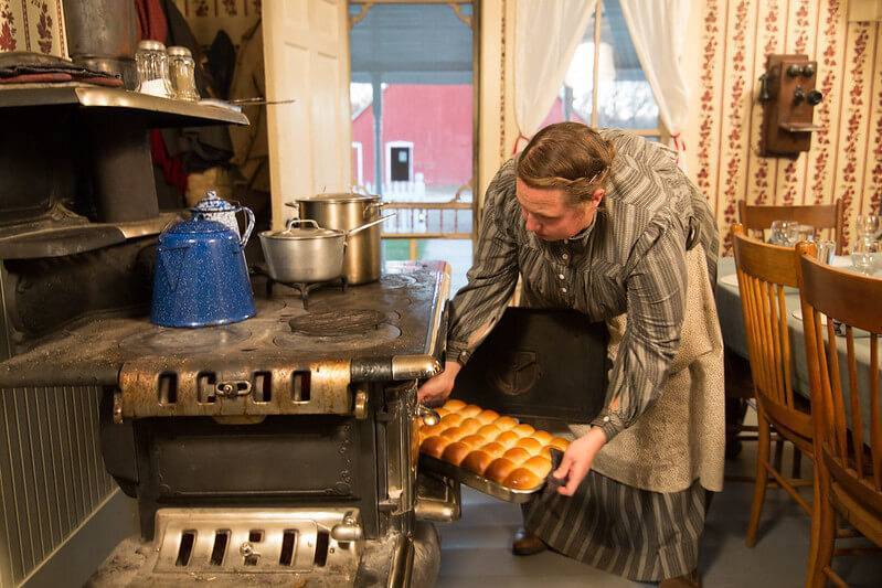 historic interpreter pulling rolls from oven
