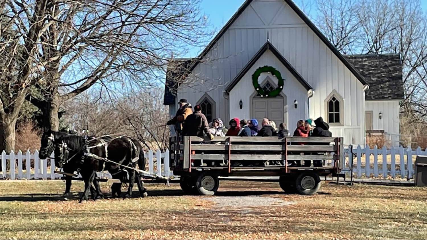 horse-drawn wagon in front of church decorated with wreath