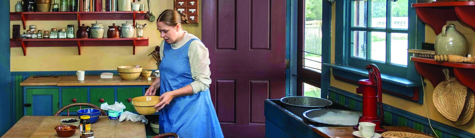 woman in period clothing working in historic kitchen