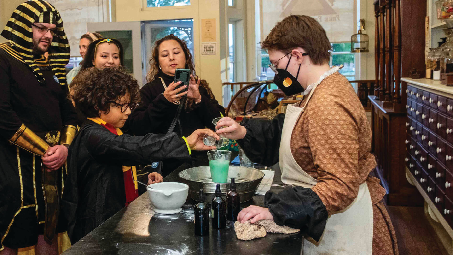 child in harry potter robes making green potion in drugstore
