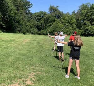 campers in a row with archery bows drawn